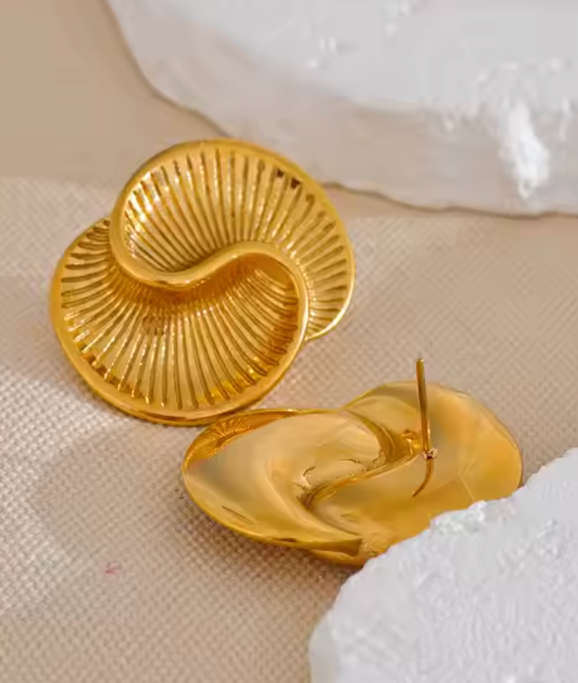 Gold-plated sculptural earrings inspired by conch shells, featuring a wavy, ridged design from the RESORT 444 Luxe Latitude Collection.